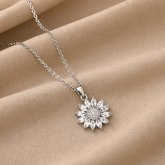 Silver flower pendant necklace displayed on soft neutral fabric