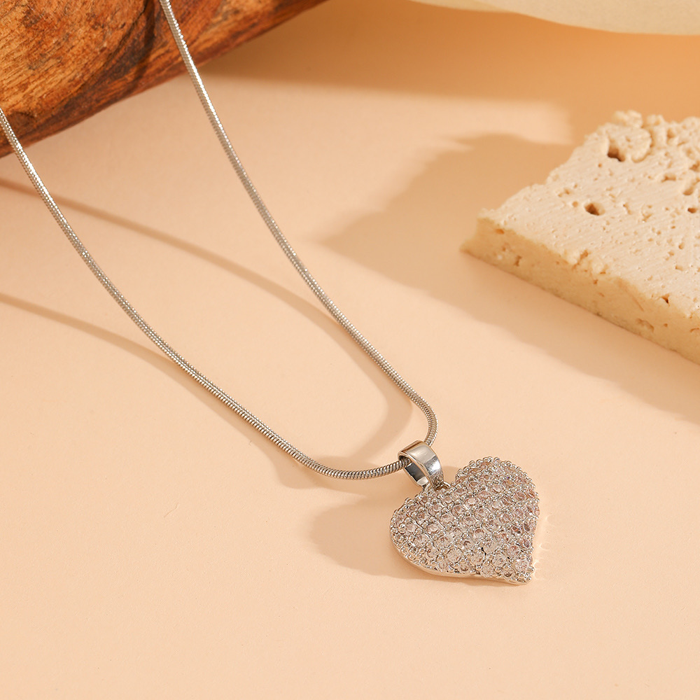 Silver heart pendant necklace with pave crystals detailing on a soft neutral background