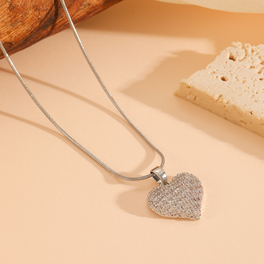 Silver heart pendant necklace with pave crystals detailing on a soft neutral background