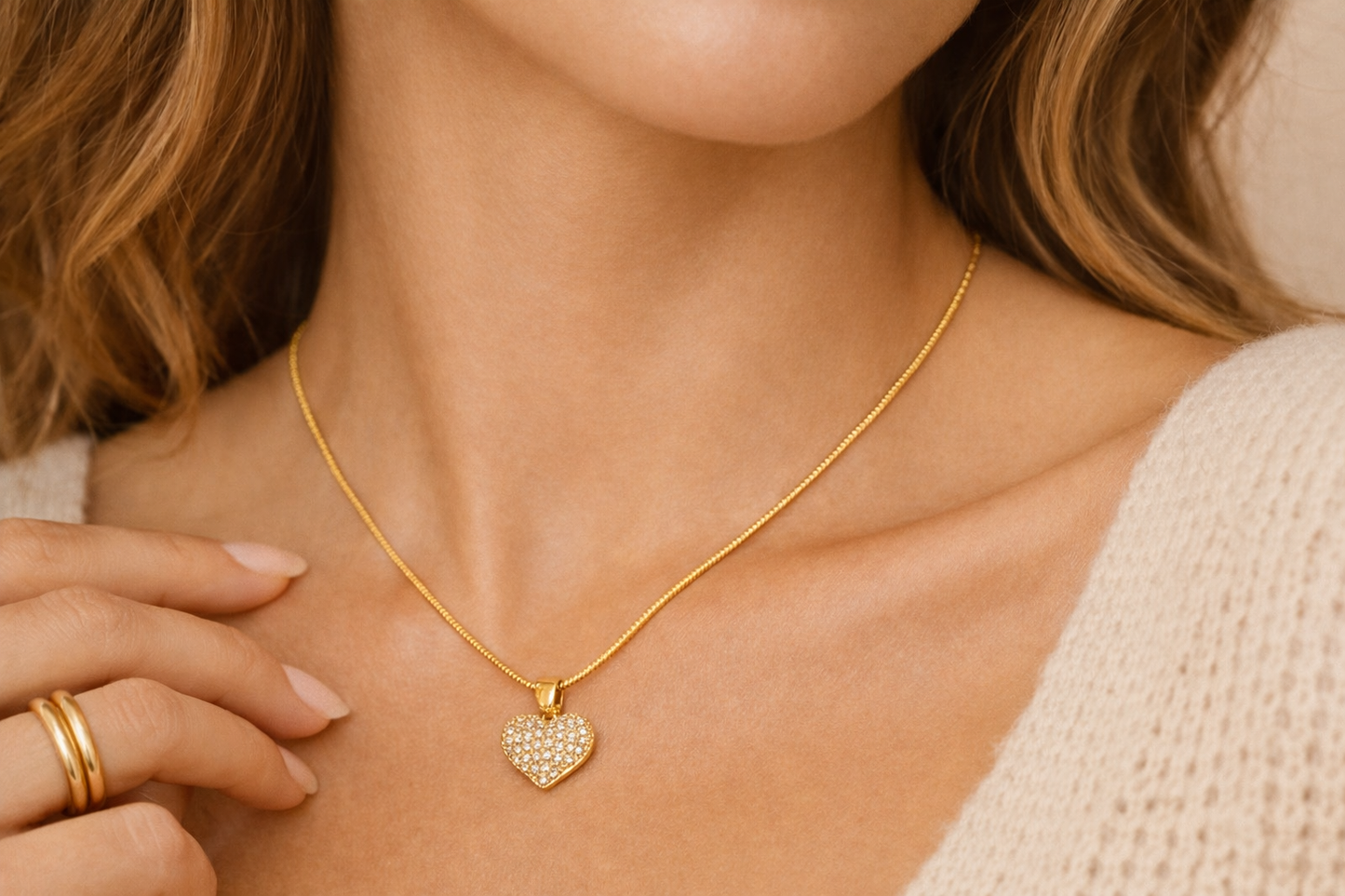 Gold heart pendant necklace worn on a model, delicate crystal heart resting on the collarbone 